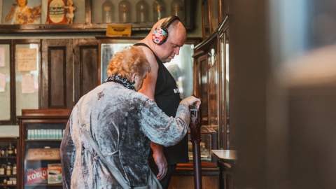 Two visitors exploring a historic shop display in Hull’s Streetlife museums , viewing wooden cabinets, vintage bottles and traditional pharmacy-style interiors.
