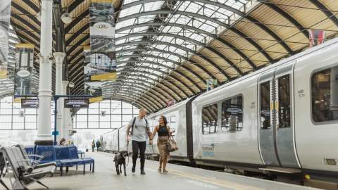A couple and a dog walk down the platform at Paragon Interchange next to a Trans Pennine Express train