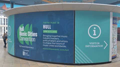 Photo taken in Paragon Interchange. Back of Welcome Information Centre avertising Hull Music Cities Convention across the height and bredth of the kiosk.