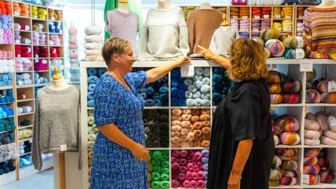 Det diskuteres strikkeoppskrifter i garnbutikken