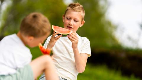 Tre damer spiser og drikker mat ved et bord utendørs