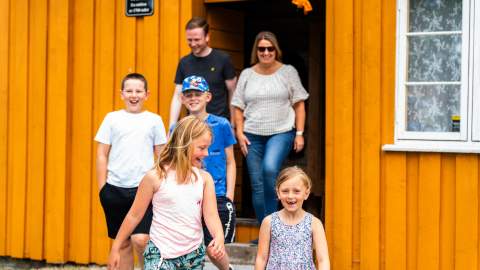Several people comes out of a yellow house