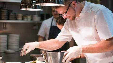 Kokk danderer mat på tallerkener på kjøkkenet til City Bar og Spiseri