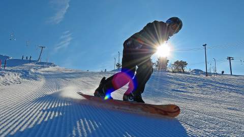 snowboarder i nypløyd bakke med sol og blå himmel i Setesdal