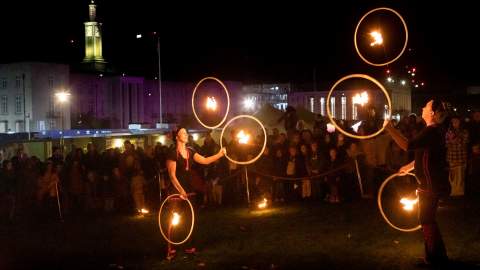Light show in Fellowship Square, Waltham Forest Town Hall campus, flame throwers on the grassy area and gardens, with crowds looking on in the evening, with the Town Hall building and clock tower in the background