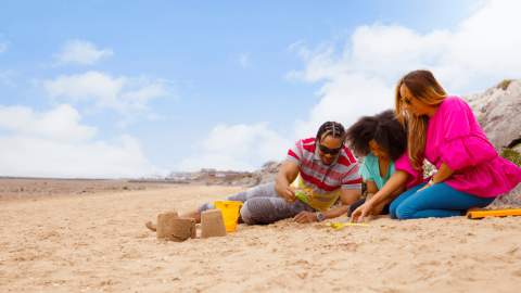 A family playing on the beach making sandcastles