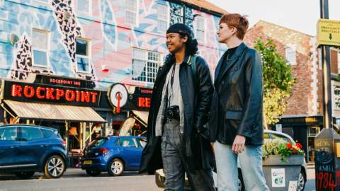 Two people walk past Rockpoint Records and street art in New Brighton.