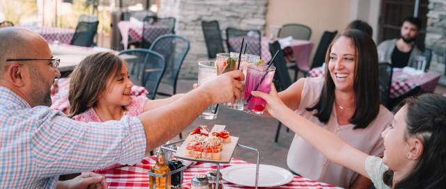 Family of 4 cheers drinks while dining at Grimaldi's on the patio.
