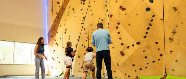 Family of 4 doing the rock climbing wall at Rush Extreme.