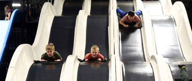 Slick City 3 kids sliding down white slides parallel.