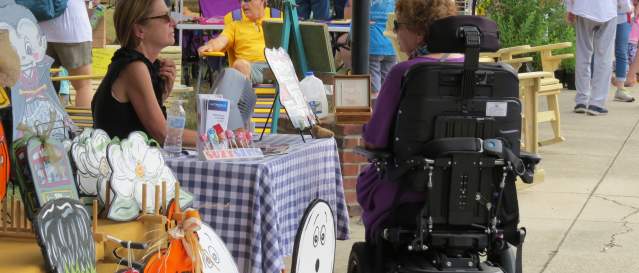 Person in wheelchair browses local artisan vendors at Mandeville Trailhead Community Market
