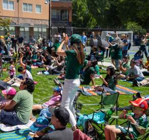 Crowd watching and applauding a soccer match outdoors at Legacy Square in Renton