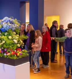 A group of people looking at a flower display in an art museum