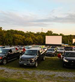 Cars parked in front of a field with a large projector