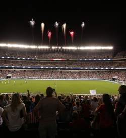 Fireworks blasting over a stadium at night filled with people