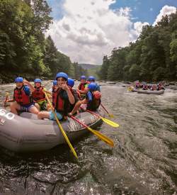 A group of people in helmets floating down a river in rafts