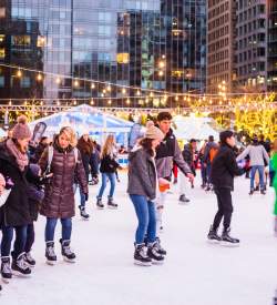 People bundled up in winter gear on an outdoor ice skating rink with twinkle lights hanging overhead