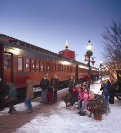 Adults and small children boarding the historic Strasburg Rail Road with snow on the ground and Christmas decorations throughout