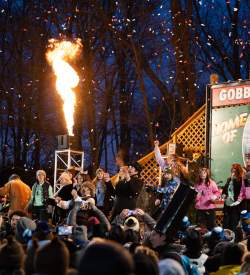 Huge crowd looking up at a stage that reads Gobblers Knob with people cheering and a blast of fire is coming out of a section of the stage