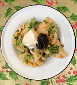 A plate of pierogies with garnish set on a decorative table cloth with holly