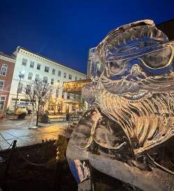 Close up of an ice sculpture shaved into Santa Claus with sunglasses on while on display on a main street