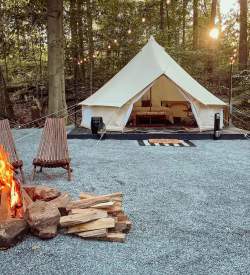 A glamping tent with a lit fire and chairs in front