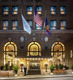 Exterior of a historic hotel with three flags hanging in front of the entrance