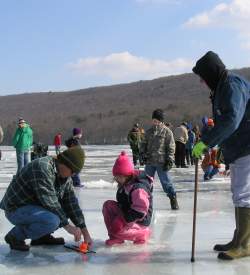 Adults and children ice fishing on a frozen lake