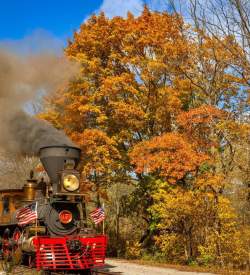 A locomotive train with fall foliage filled trees in the background