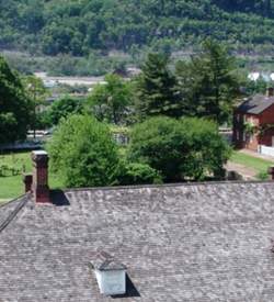 Aerial view of five red brick buildings with white trimming and a garden with a clear path and a fountain in the middle.
