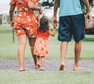 Little girl holding hands with parents