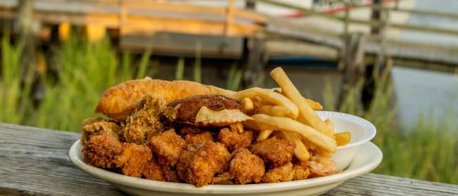 a plate of Calabash style seafood and fries on an outdoor railing in Calabash, NC