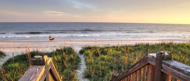 Walkway to a sandy path leading to Holden Beach at sunset.