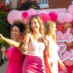Women dancing in front of pink balloons