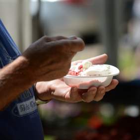 Hands holding a bowl of strawberry dessert