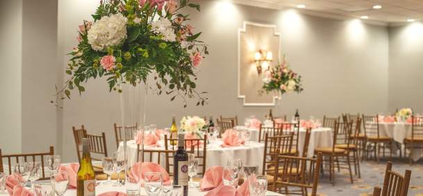 Ballroom set up with pink and white decor and flower center pieces at the MCM Elegante Beaumont