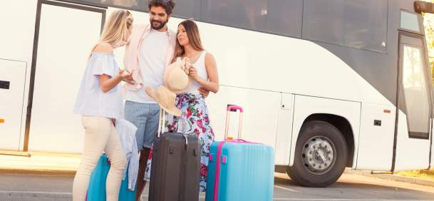 three people standing in front of transit with luggage