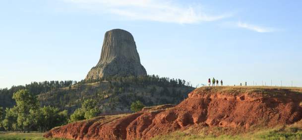 Hiker walking along a trail surrounded by lush greenery in Wyoming at sunrise