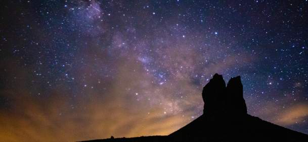 Boar's Tusk, a sentinel of Sweetwater County, stands sharp and silent against the infinite canvas of the night. Above the rugged butte, the stars ignite the sky with a cold, pristine brilliance, mirroring the untamed spirit of Wyoming. This is more than a landscape; it's a moment where the ancient earth meets the cosmos, cloaked in the deep, velvet darkness of a high-desert night.