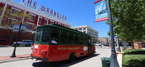 Red and green trolley passing through historic streets during a Cheyenne Trolley Tour in Laramie County, Wyoming.