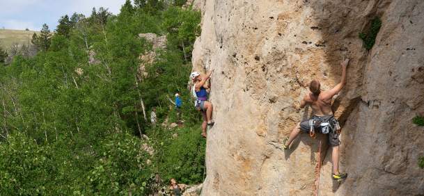 Rock climbers scaling a mountainside in the forest.