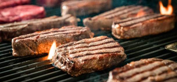 Beef steaks on a fiery grill.