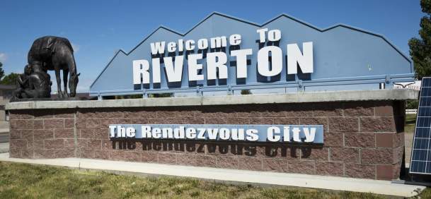 Welcome sign for Riverton, Wyoming, set next to a bronze statue in Fremont County.
