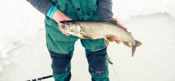 Angler ice fishing on a frozen lake with fish in hands in Wyoming.