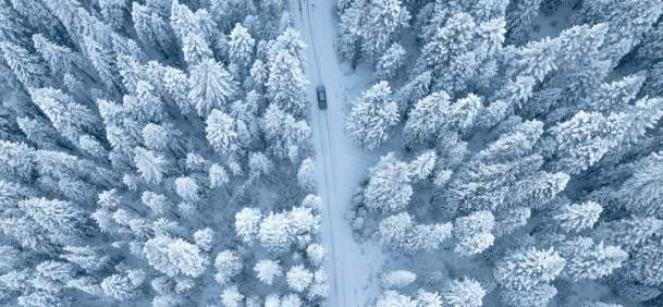 Aerial view of car driving downm a snowy road in Wyoming winter.