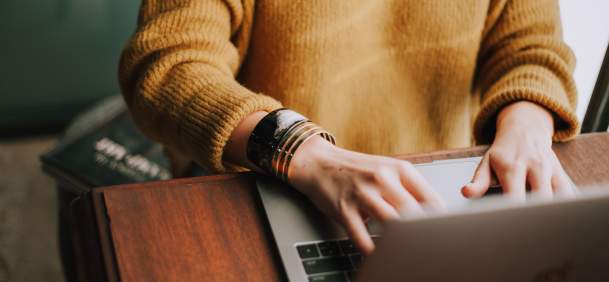 person at desk, typing on laptop