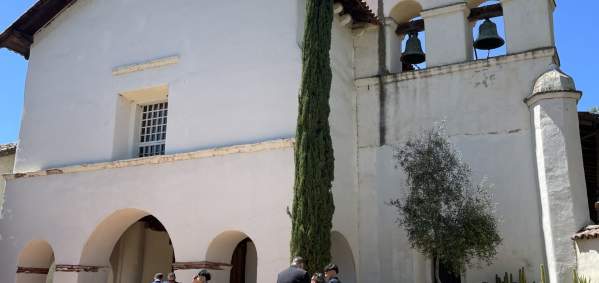 San Juan Bautista Mission. People stand in front of the Mission entryway and Bell Tower.