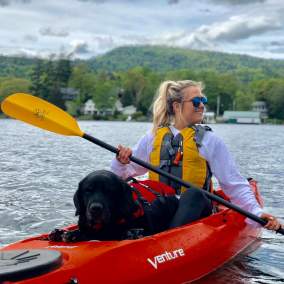 Woman and dog kayaking through lake george