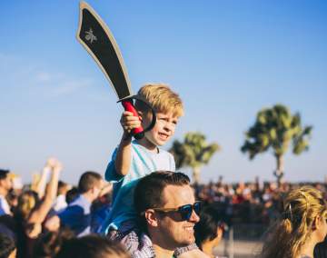 little boy on father's shoulder at Children's Gasparilla
