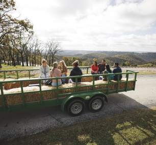 A group riding on a hayride with rolling hills in the background